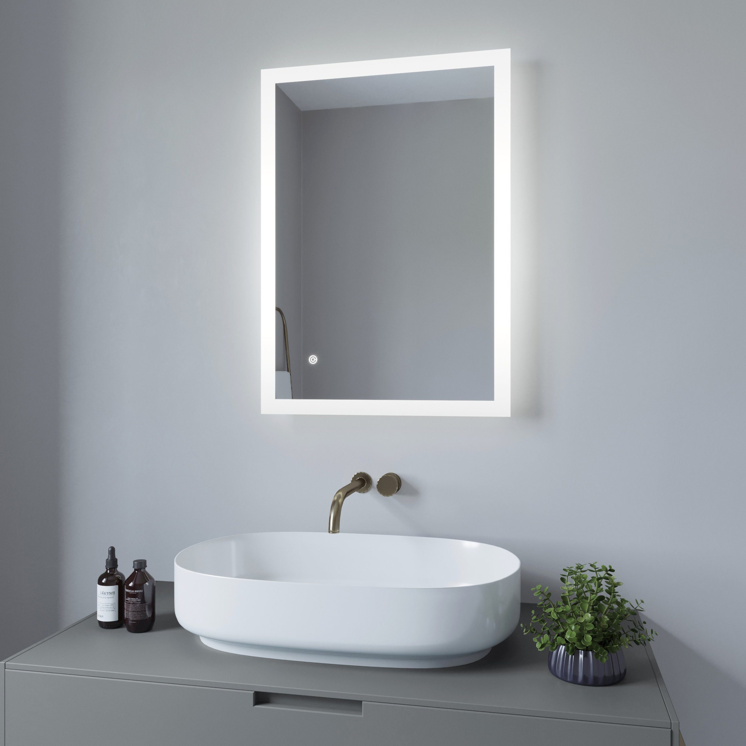 Badezimmerspiegel mit LED-Leuchten über einem Waschbecken mit Wasserhahn und Toilettenartikeln. Grauer Wandhintergrund.