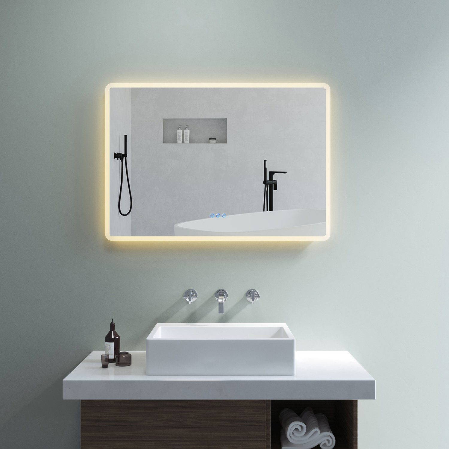Ein Badezimmerspiegel mit Lichtern am Rand. Ein Waschbecken und Wasserhahn befinden sich darunter. Eine Wanne wird reflektiert.