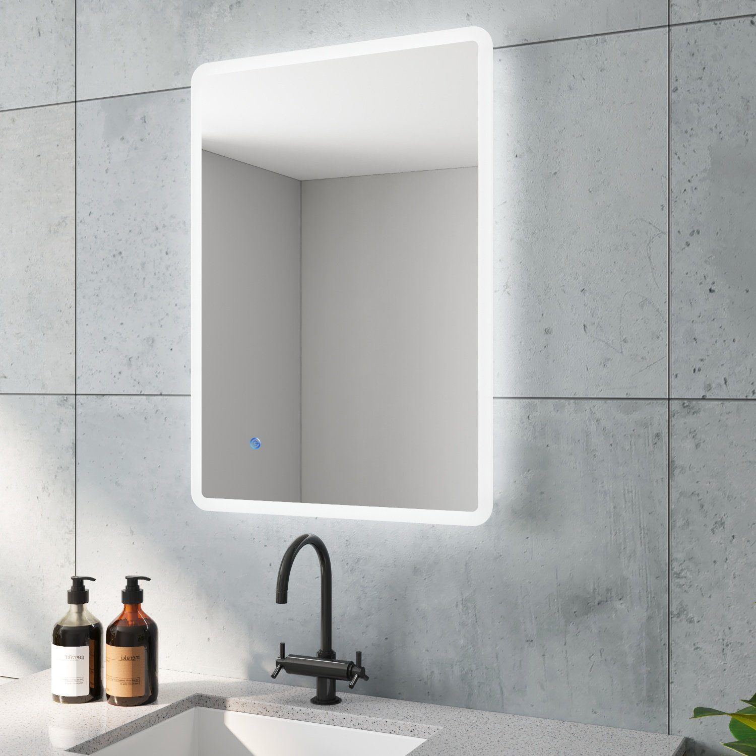 Ein moderner Badezimmerspiegel mit LED-Leuchten, Wasserhahn und Seifenflaschen vor einer grauen Wand.