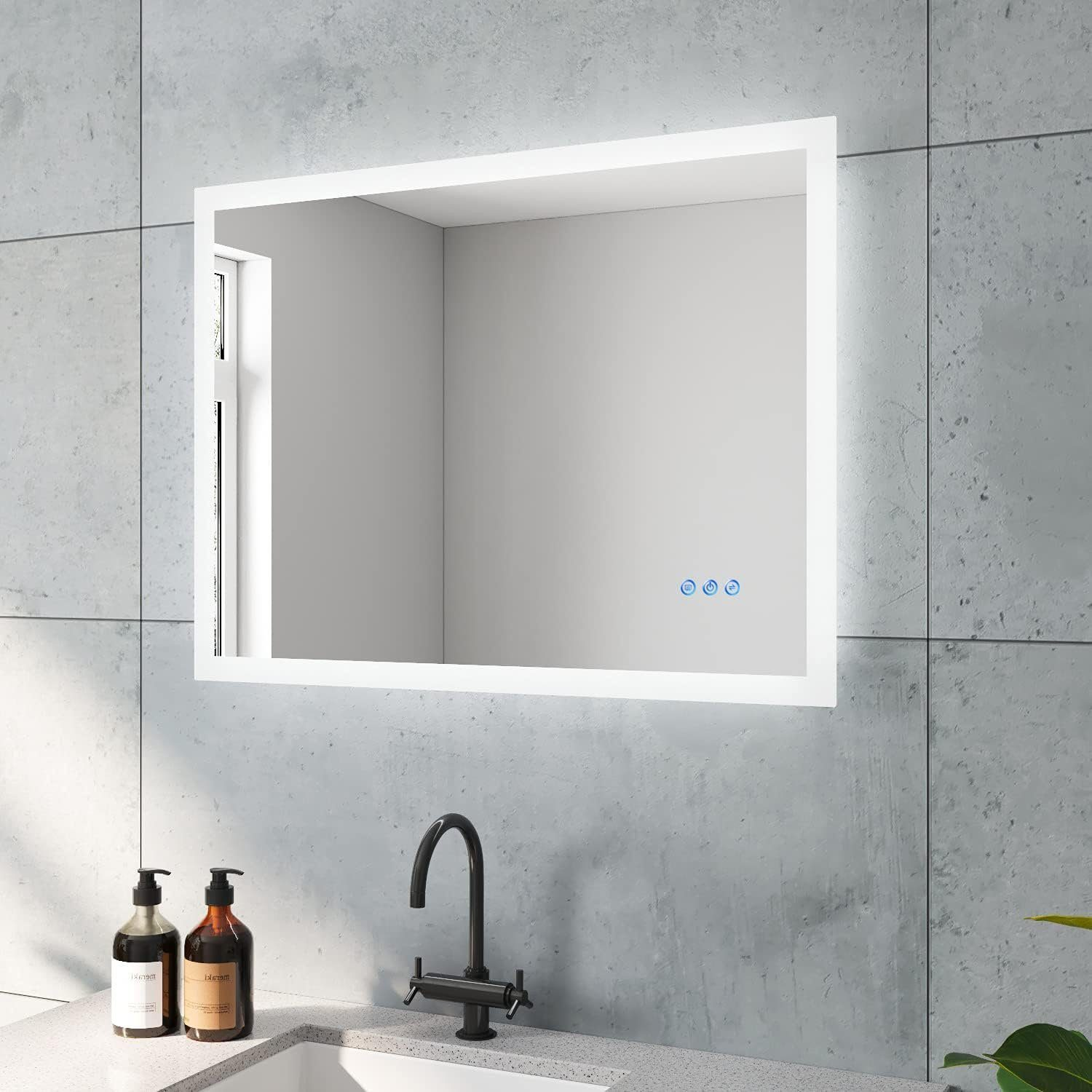 Badezimmer mit großem rechteckigen Spiegel mit Lichtern, Waschbecken, Wasserhahn und Flaschen auf der Theke.