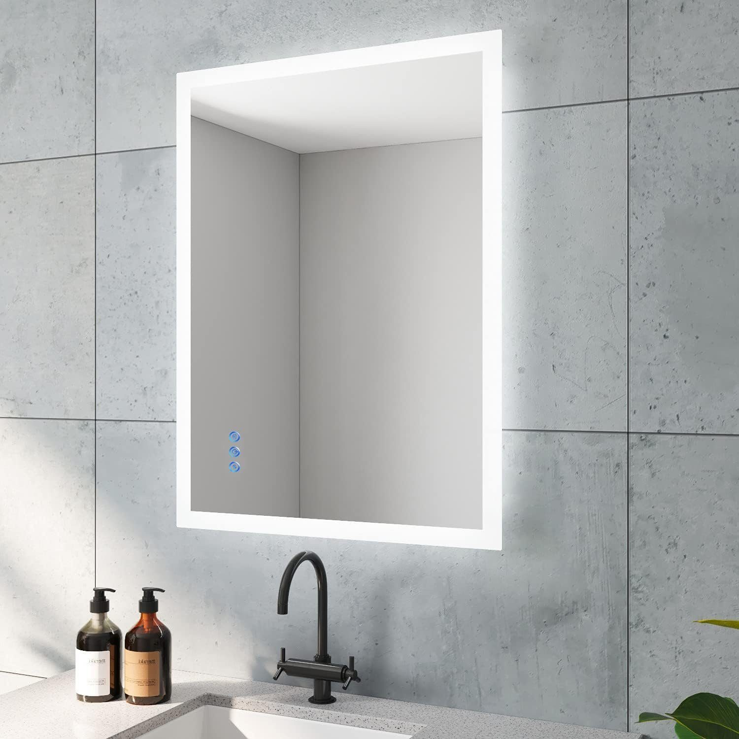 Badezimmerspiegel mit weißem Rahmen und Lichtern. Drei blaue Touch-Tasten sind sichtbar.