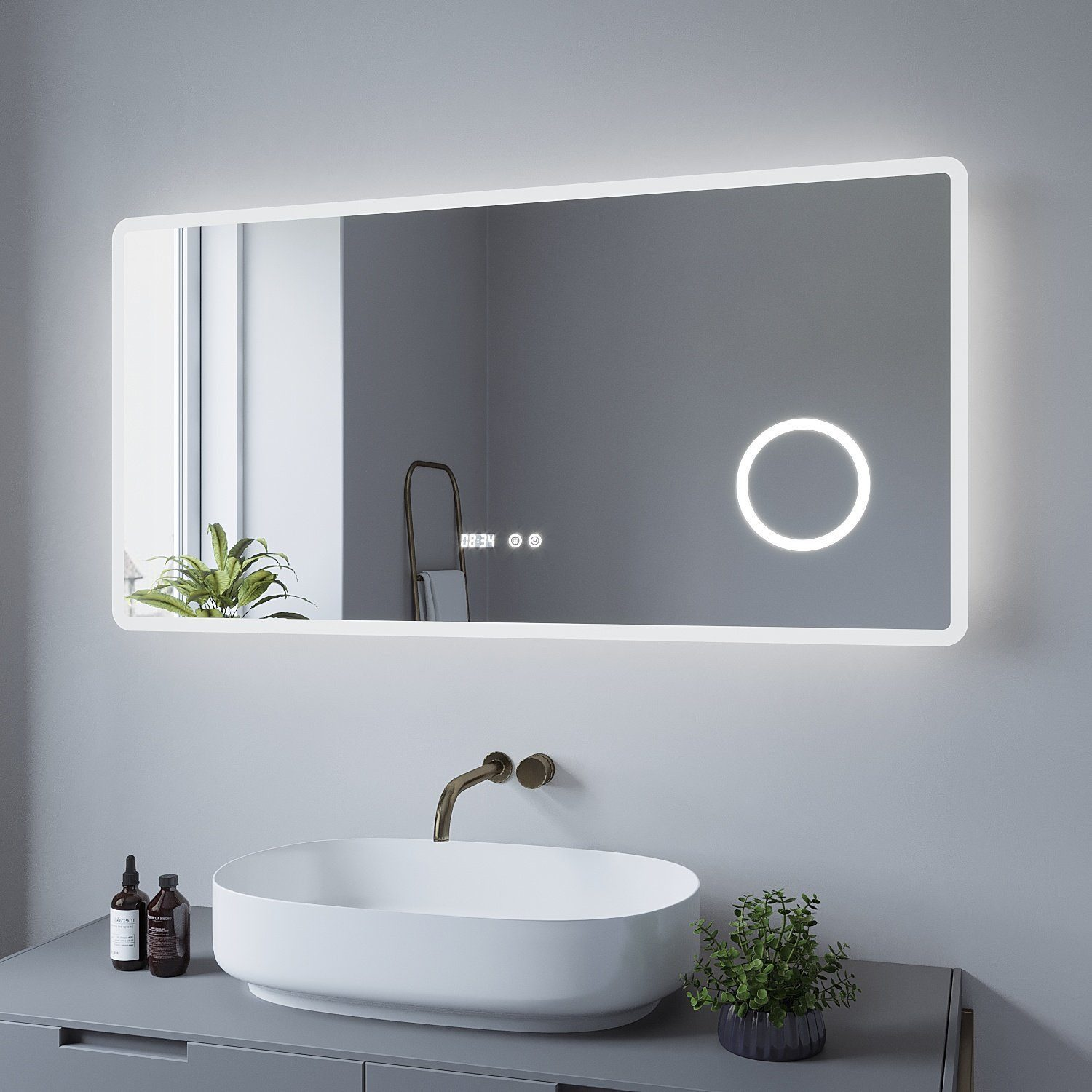 Badspiegel mit LED-Beleuchtung. Er befindet sich über einem Waschbecken mit Wasserhahn und Dekorationsartikeln.