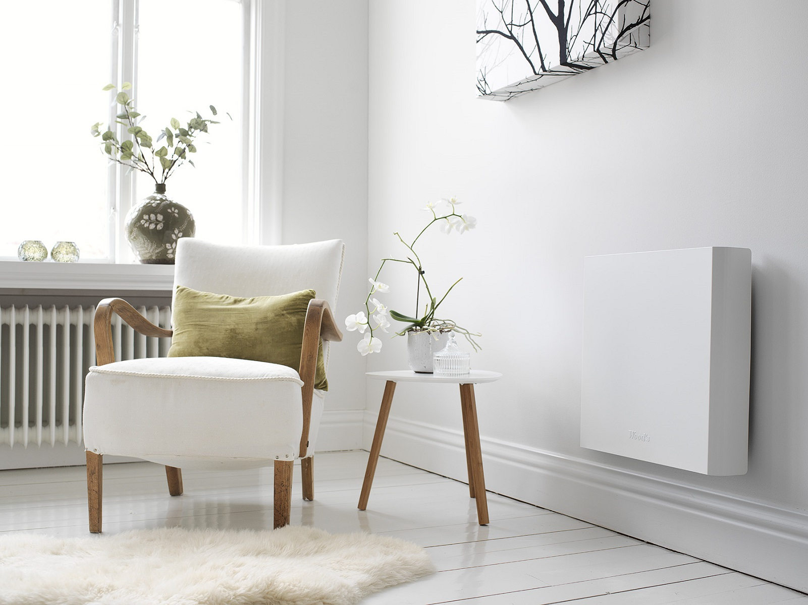 Ein weißes Zimmer mit weißem Stuhl, kleinem Tisch und weißem Wandheizkörper.