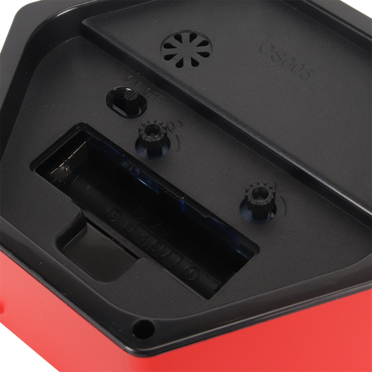 Nahaufnahme des Inneren eines rot-schwarzen Weckers, mit Batteriefach und Zahnrädern.