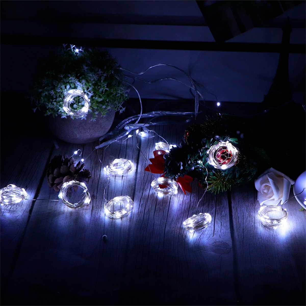 Lichterketten mit weißen LEDs, angeordnet auf einer dunklen Holzoberfläche. Einige Lichter sind aufgerollt.