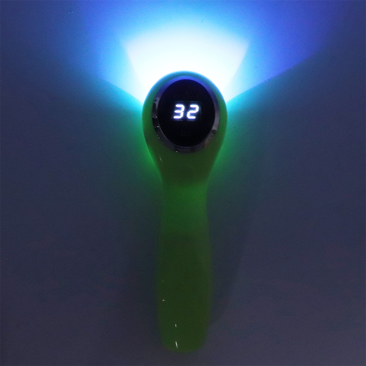 Grünes Gerät, das blaues Licht aussendet. Eine Digitalanzeige zeigt '32'. Die Szene ist auf grauem Grund.