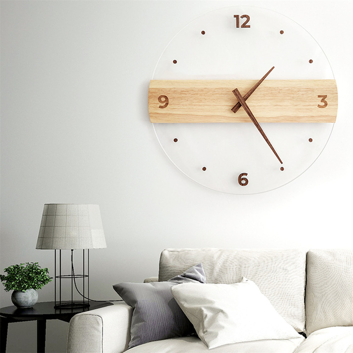 Eine moderne Uhr mit Holzakzenten an einer weißen Wand, über einem Sofa und einer Lampe.