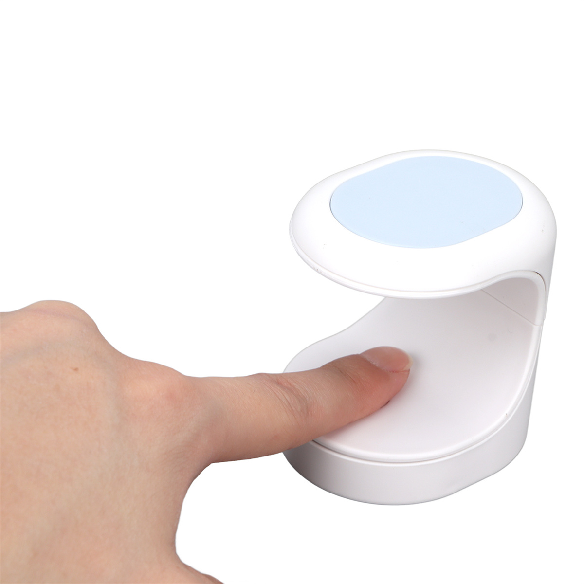 Eine weiße Nagelhärtungslampe. Ein Finger befindet sich in der Lampe. Der Hintergrund ist weiß.