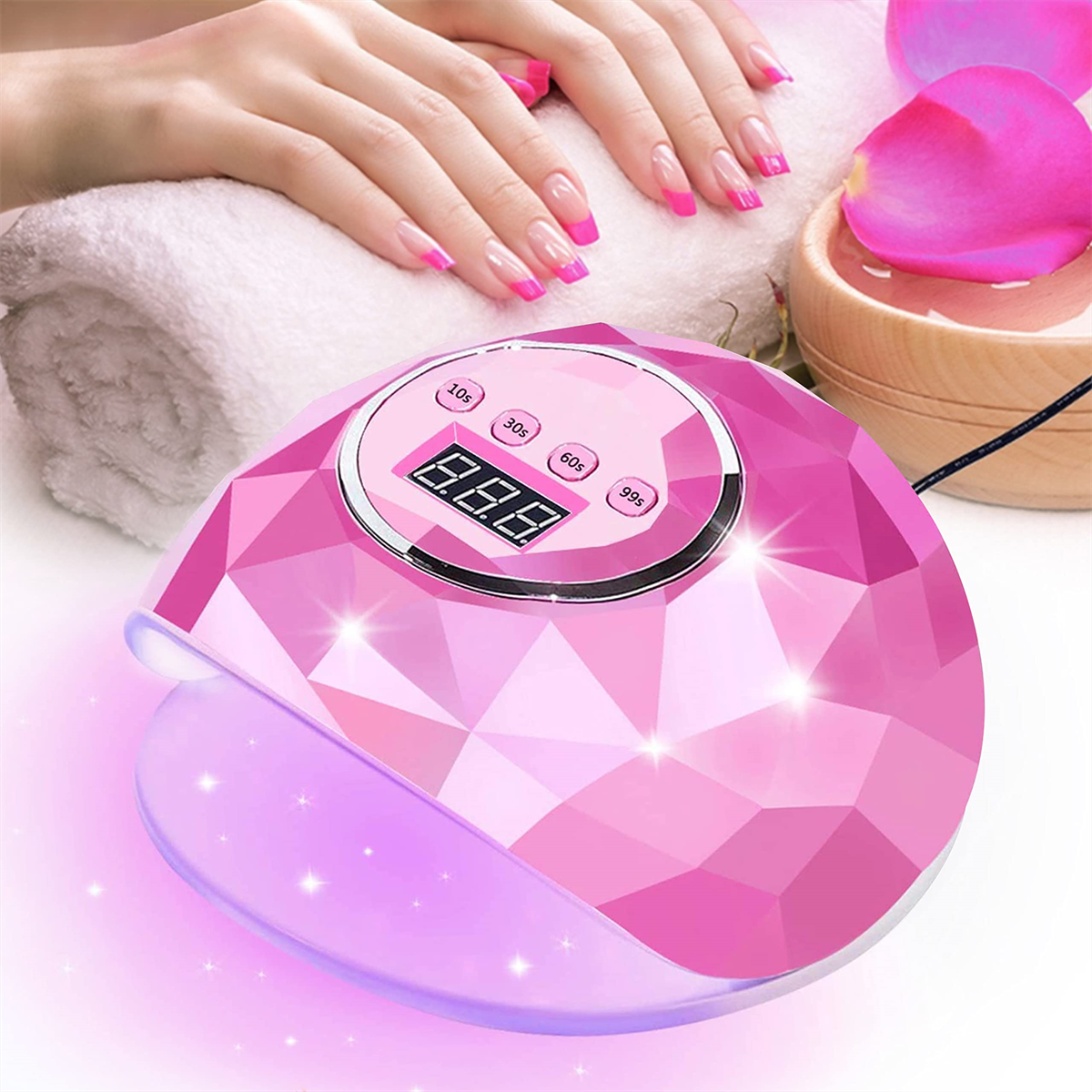 Rosa Nagellampe mit Timer und Hand, und rosa Rosenblätter in einer Schale.