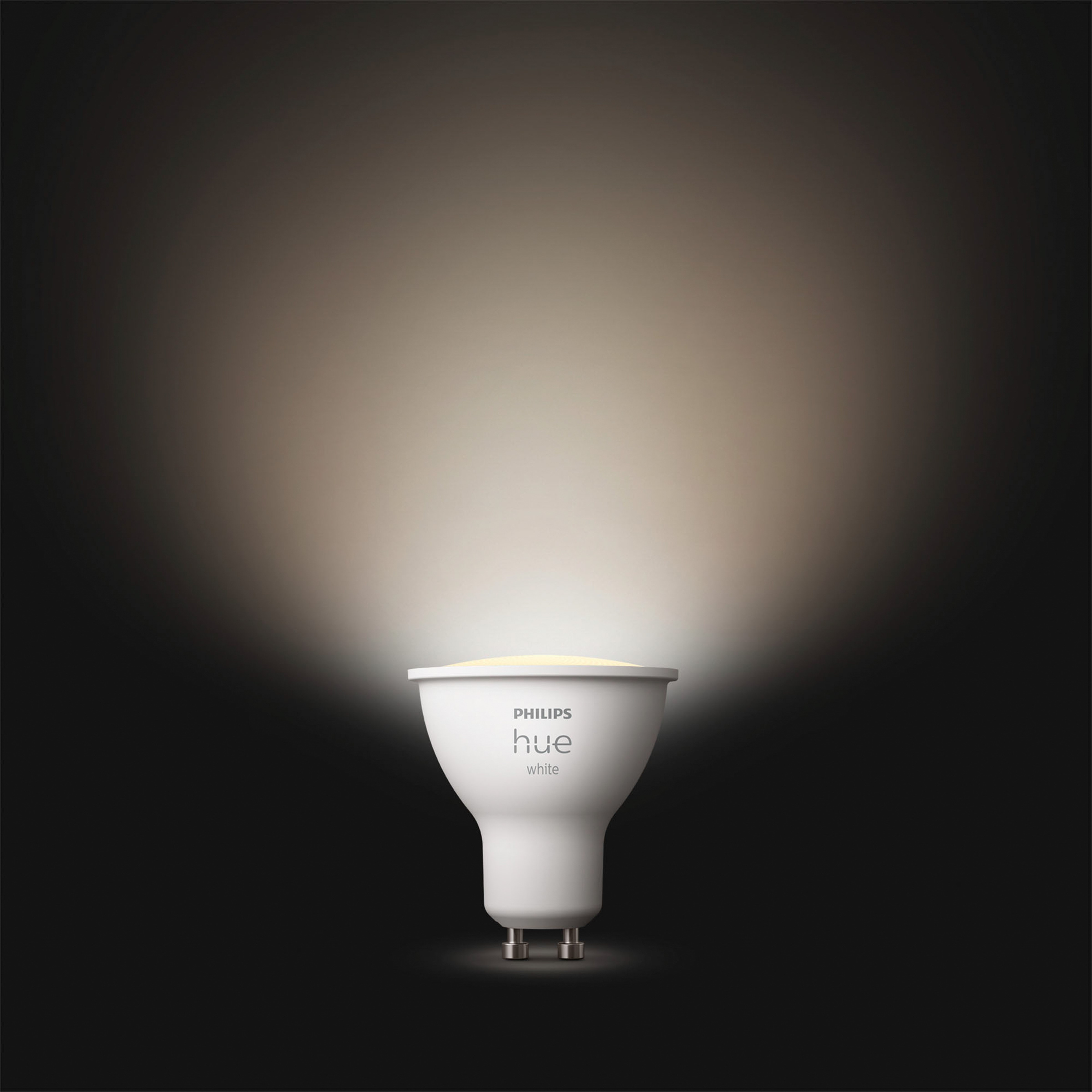 Une ampoule Philips Hue blanche sur fond sombre, avec un faisceau lumineux puissant.