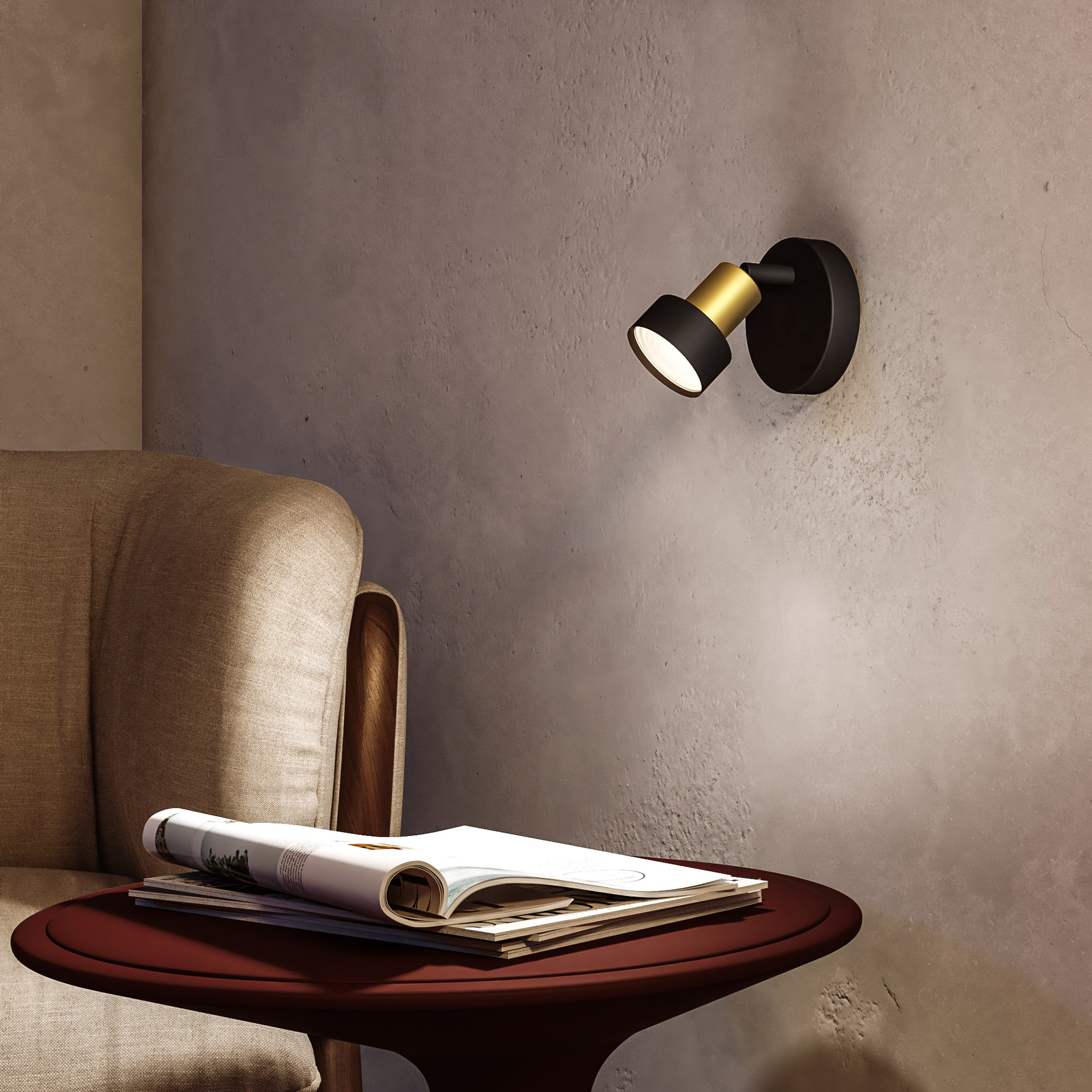 Un spot noir et or sur un mur, avec une table et des magazines devant.