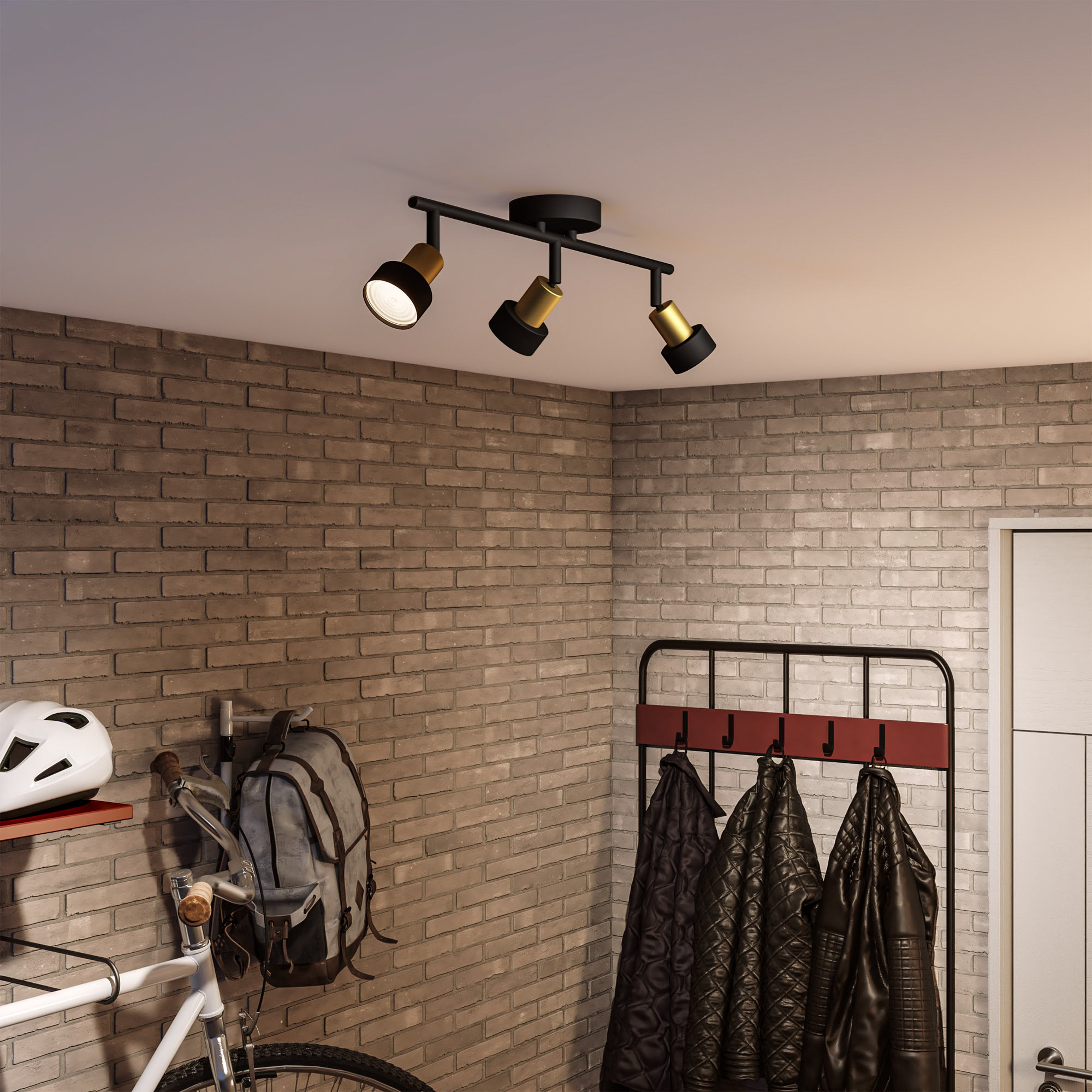 Drie spots, een bakstenen muur, een fiets, een kapstok en een witte deur.