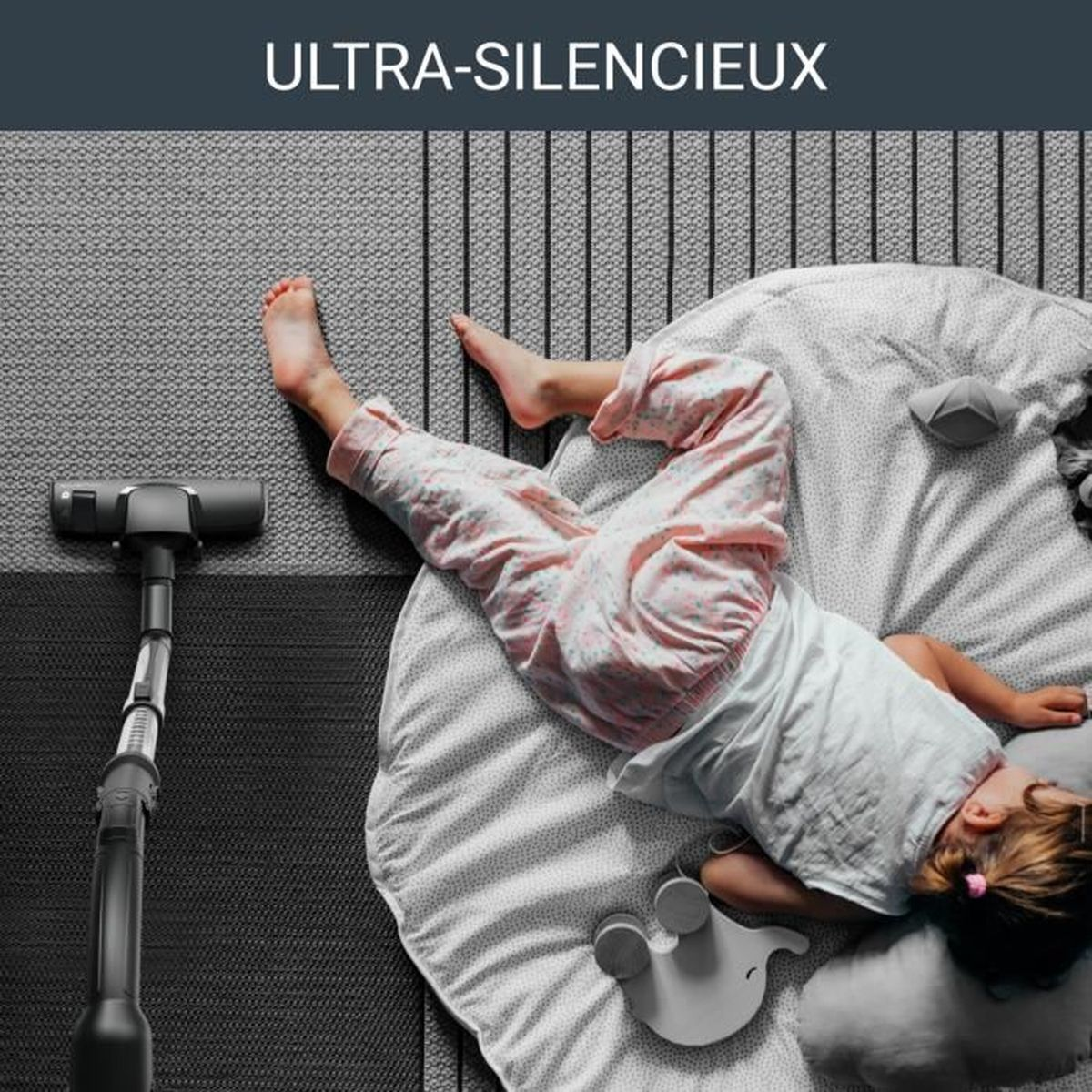 Dziewczynka śpi na łóżku z odkurzaczem w lewym pierwszym planie.