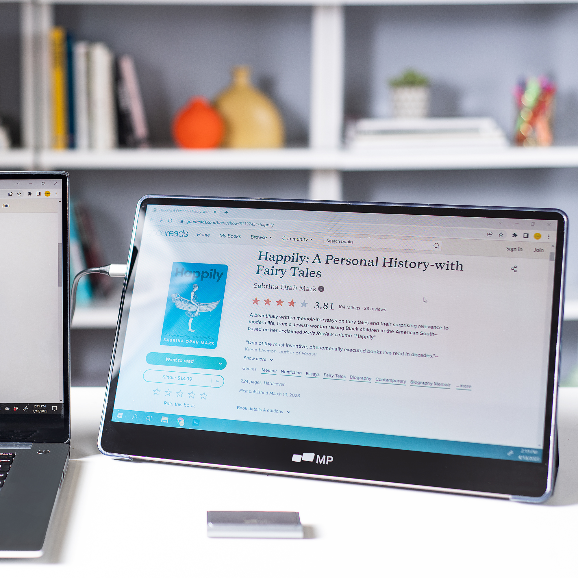 Laptop mit geöffneter Lese-App. Ein Buchcover und Text sind sichtbar. Ein kleines Gerät befindet sich unten.