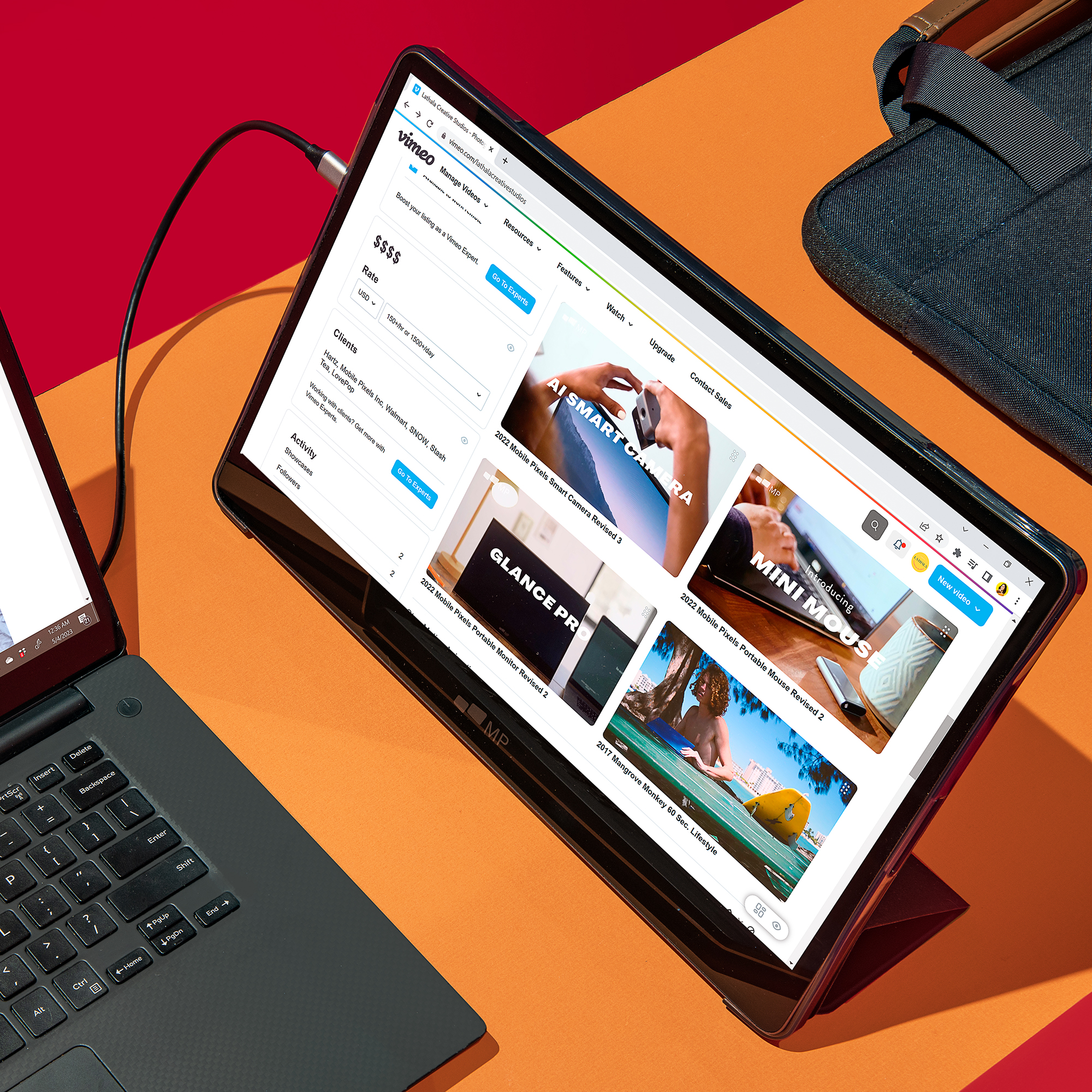 Ein Laptop und ein Tablet mit Website-Anzeige liegen auf einer orangefarbenen Oberfläche.