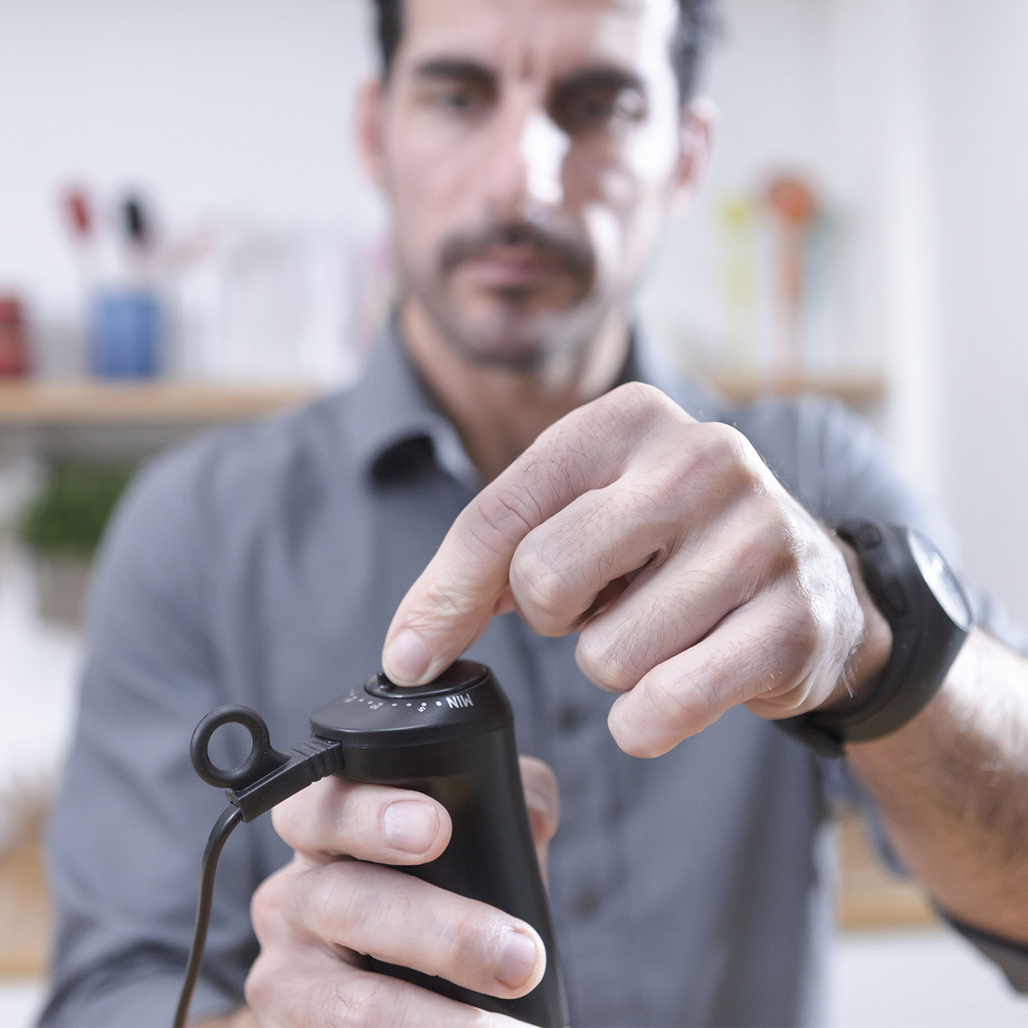 Ręce mężczyzny na czarnym blenderze. Włącza przełącznik na blenderze.