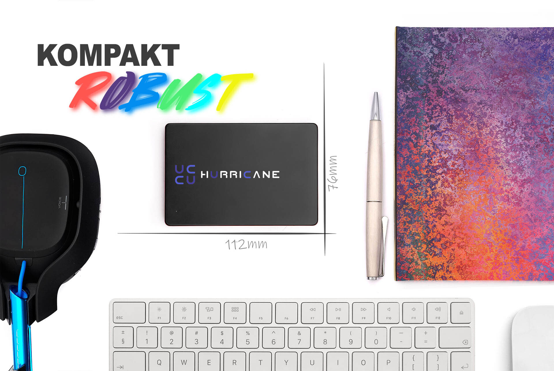 Ein Schreibtisch-Setup mit einer schwarzen SSD, einem Stift, einer Tastatur und einem Notizblock. Die SSD trägt die Aufschrift "HURRICANE".
