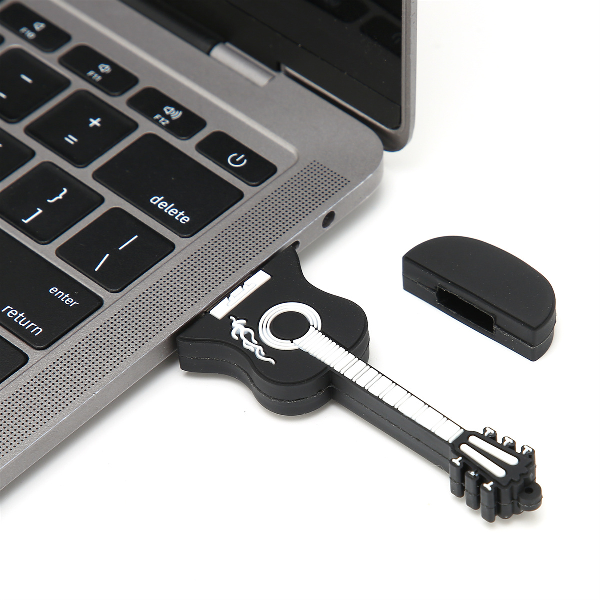 Ein schwarzer USB-Stick in Gitarrenform, der in einen Laptop gesteckt ist. Der Stick hat ein weißes Gitarrendesign.