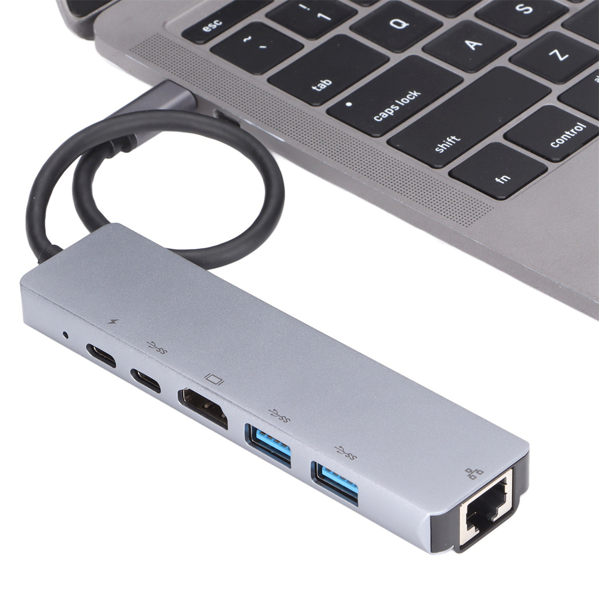 Ein grauer USB-C-Hub, der mit einem Laptop verbunden ist. Es hat mehrere Anschlüsse.