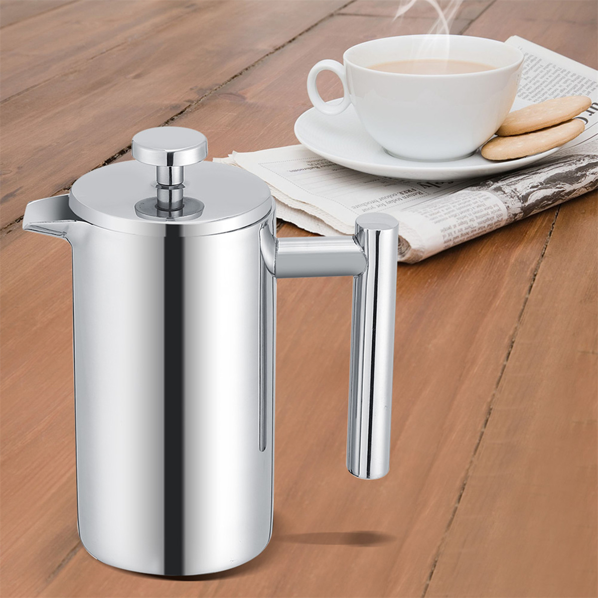 Eine silberne French-Press-Kaffeemaschine auf einem Holztisch mit Kaffee und Keksen.