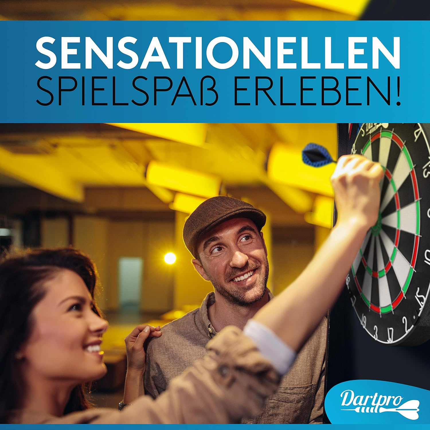 Ein Mann wirft einen Dartpfeil auf eine Dartscheibe und lächelt. Eine Frau steht neben ihm und lächelt.