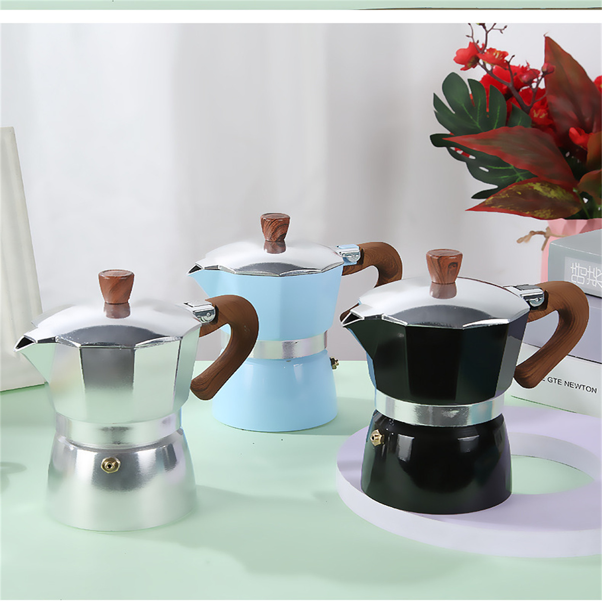 Drei bunte Kaffeemaschinen. Silber, blau und schwarz.