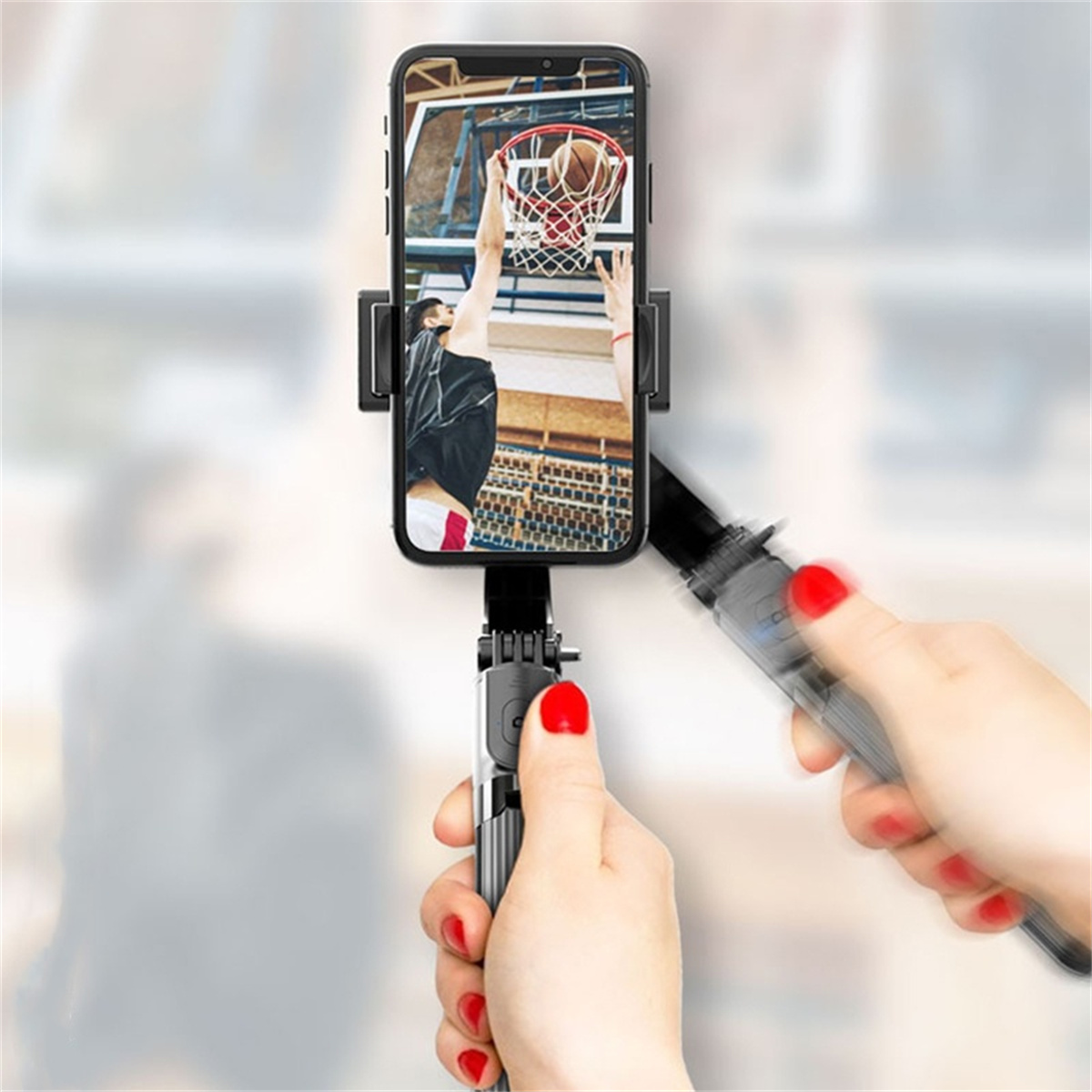 Eine Person hält ein Telefon auf einem Selfie-Stick und nimmt ein Basketballspiel auf.