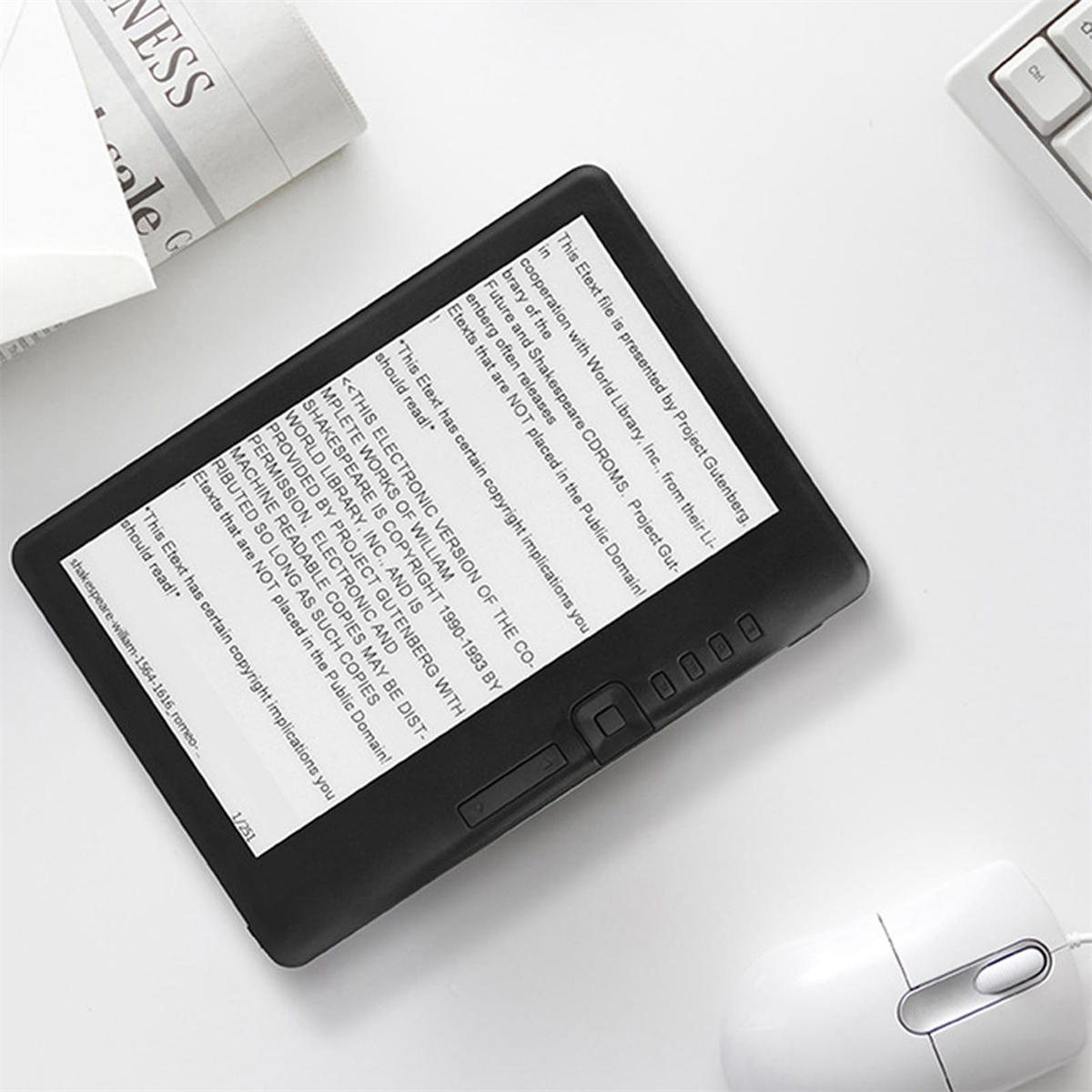 Schwarzer E-Reader mit Text. Maus und Tastatur auf weißer Oberfläche.