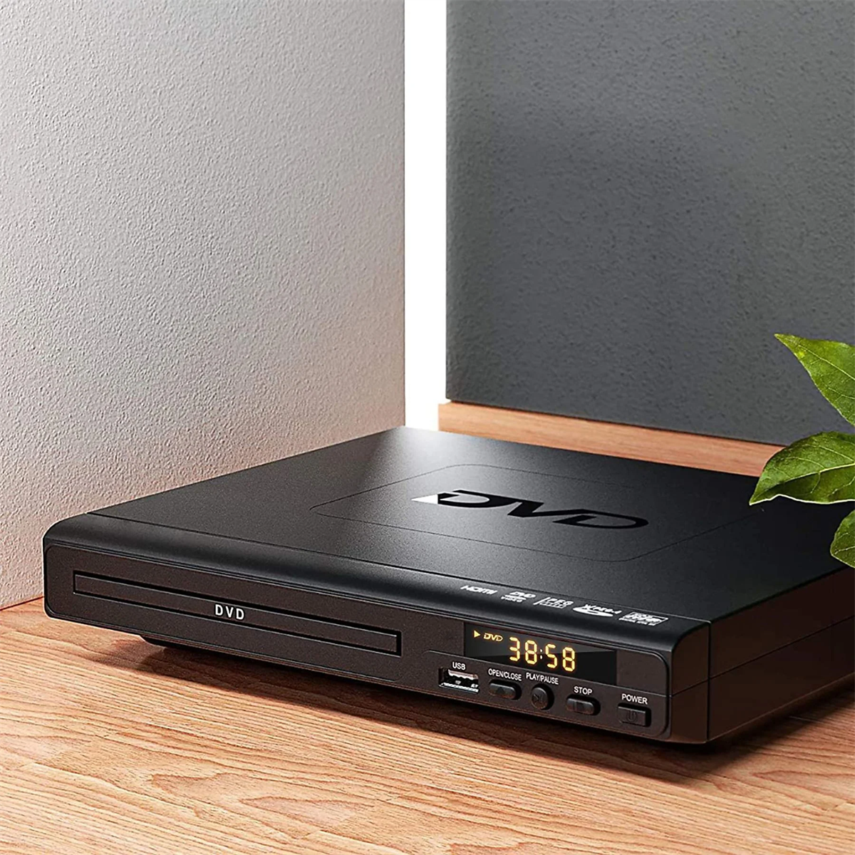 Ein schwarzer DVD-Player auf einer Holzoberfläche. Das Display zeigt 38:58 an. Verfügt über DVD- und USB-Anschlüsse.