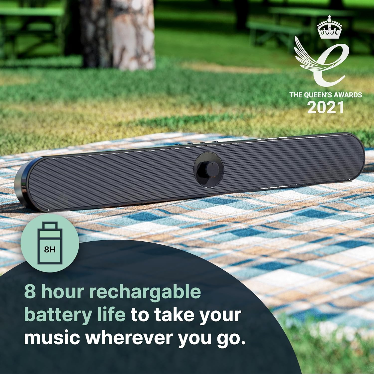 Zwarte soundbar op een picknickkleed. Het heeft een batterijduur van 8 uur en een volumeknop.