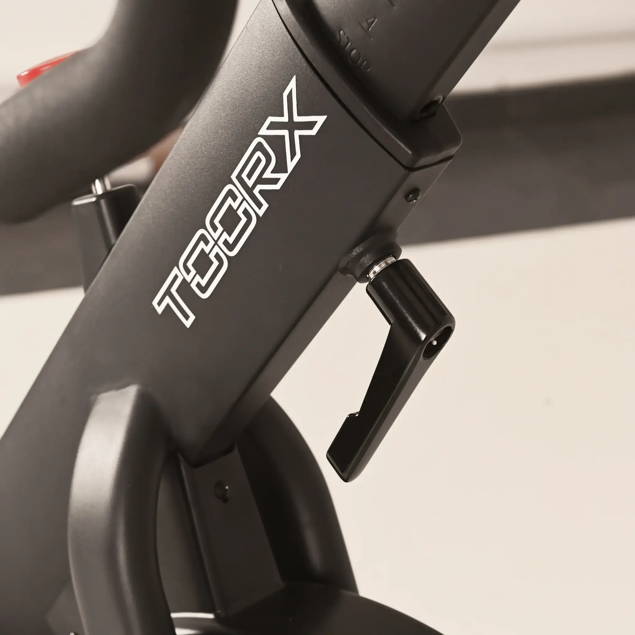 Een close-up van de zwarte verstelhendel van een hometrainer met witte 'TOORX'-tekst.