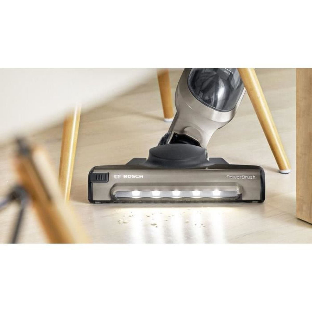 Primer plano de un cabezal de aspiradora en un suelo de madera. La aspiradora es gris con el logo de Bosch.