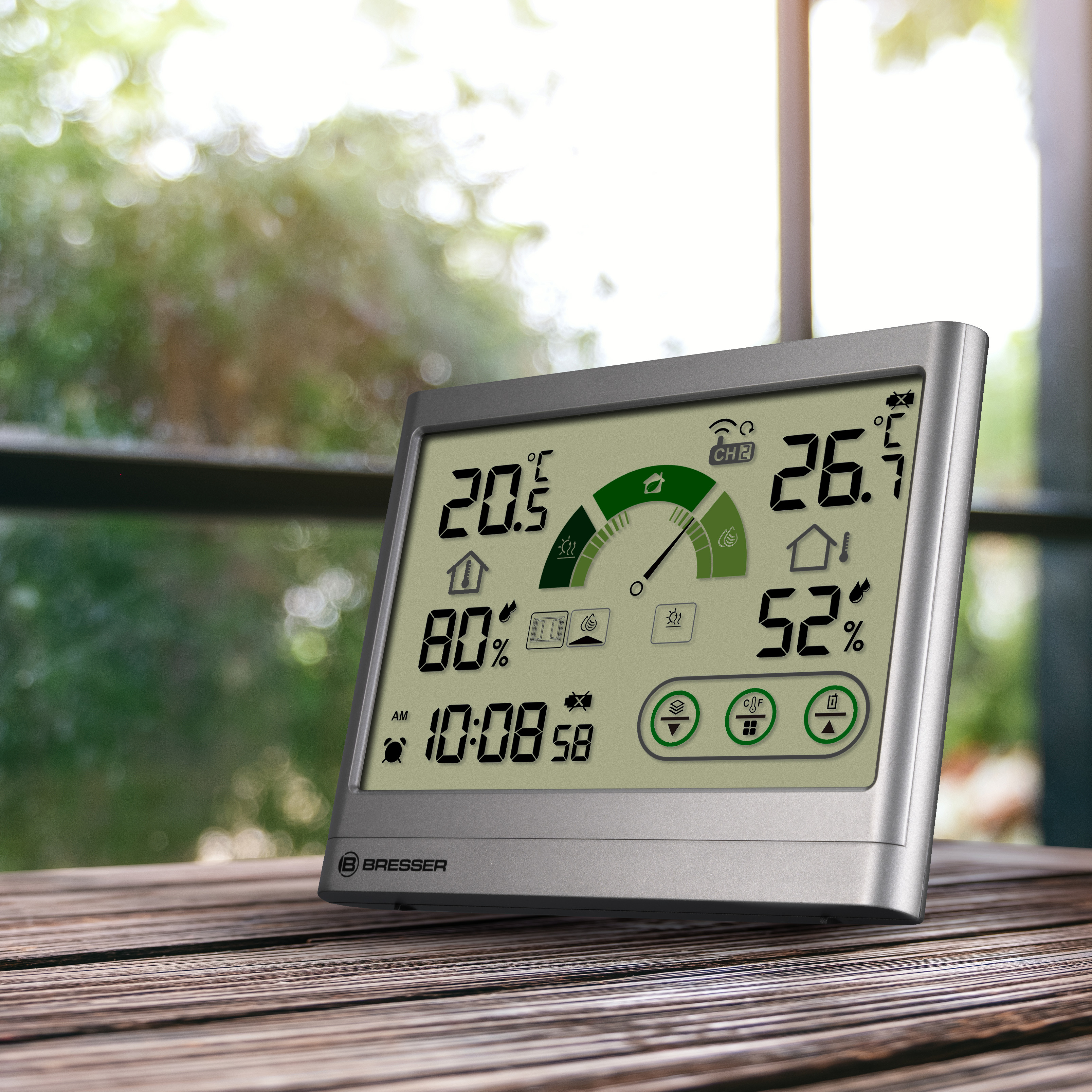 Estación meteorológica digital muestra temperatura, humedad y hora. Está sobre una mesa de madera cerca de una ventana.