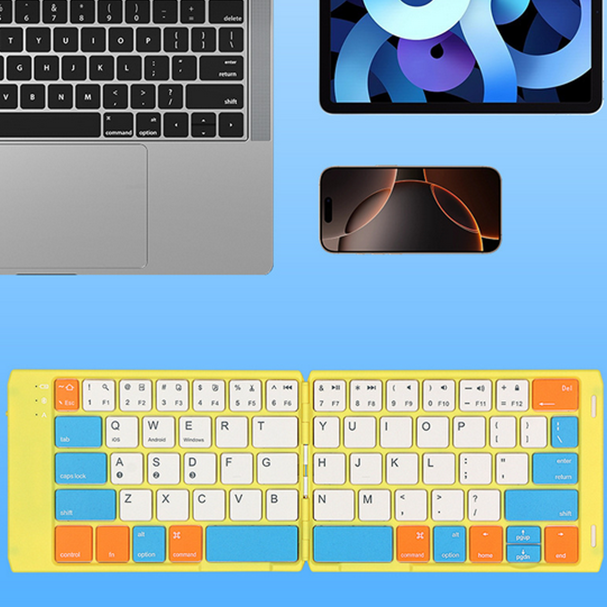 Laptop, Tablet und eine gelbe, zusammenklappbare Tastatur auf einem Tisch. Draufsicht.