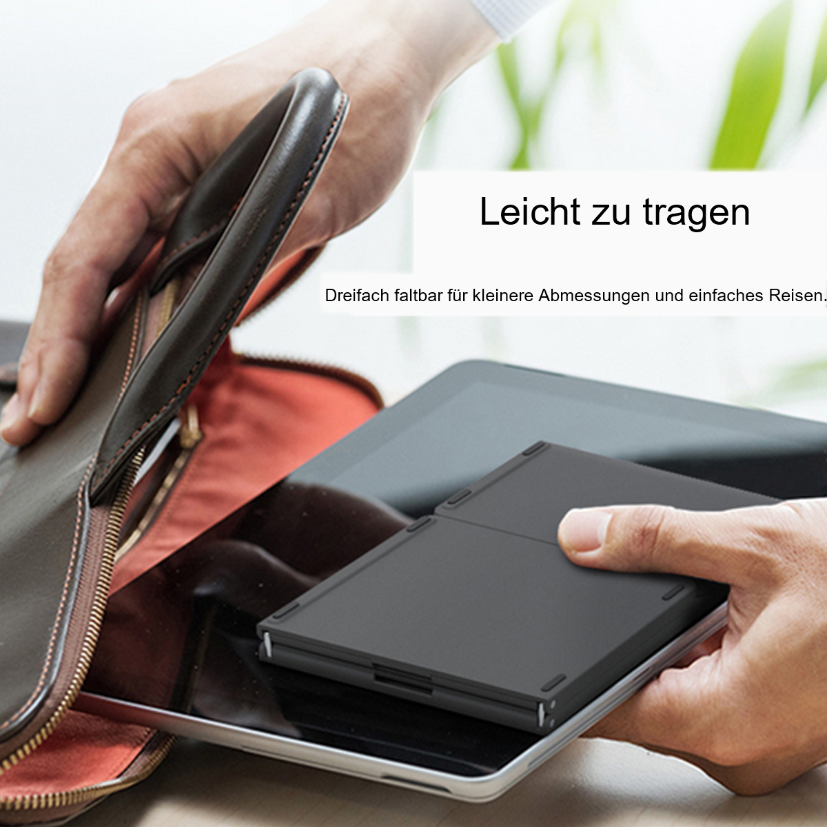 Schwarze, faltbare Tastatur liegt auf einem Tablet, neben einer Ledertasche, leicht tragbar.