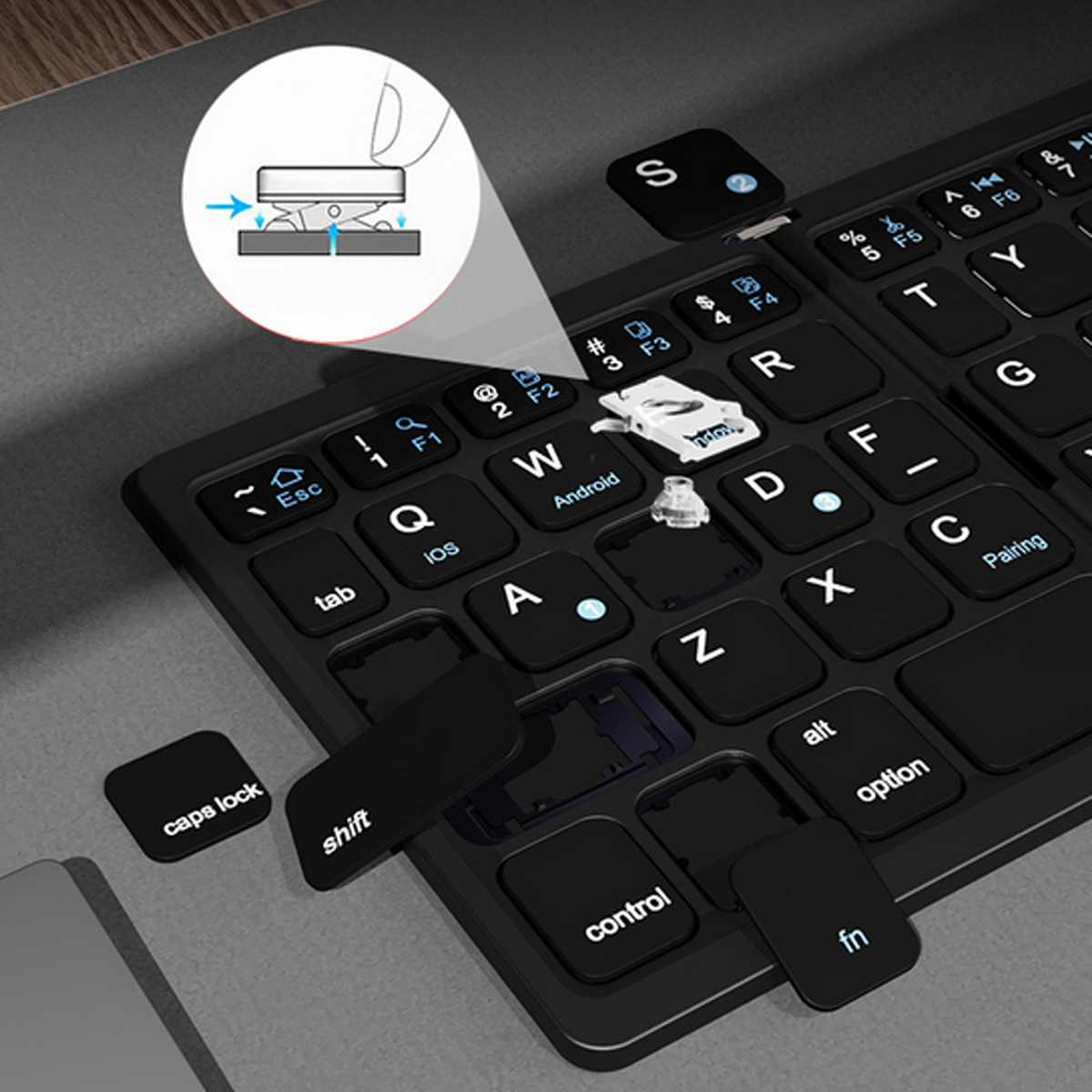 Schwarze Tastatur mit abgenommenen Tastenkappen. Ein Diagramm zeigt, wie die Kappen entfernt werden.
