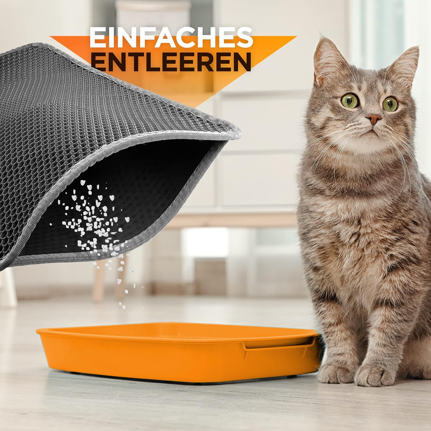 Eine getigerte Katze sitzt in der Nähe einer Katzentoilette mit einer grauen Matte. Die Matte wird entleert.