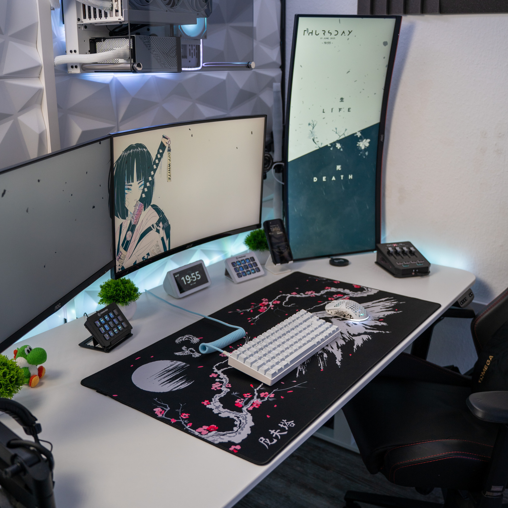 Gaming-Schreibtisch mit Monitoren, Tastatur, Maus und Dekorationsartikeln.