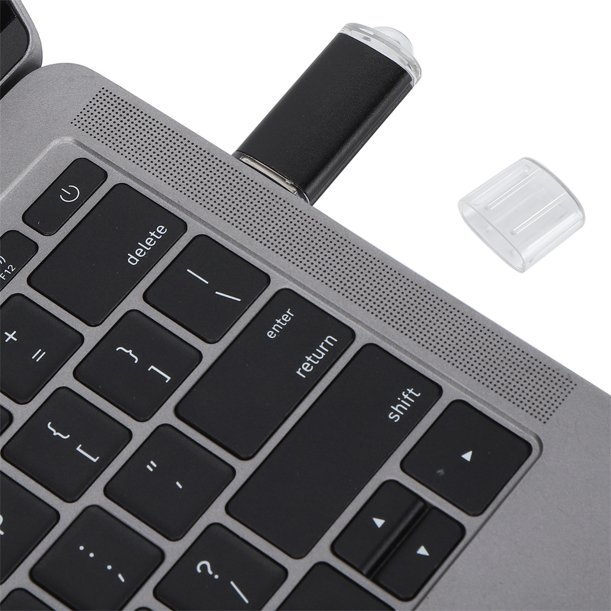 Laptop-Tastatur mit eingestecktem USB-Stick und abgenommener USB-Stick-Kappe.