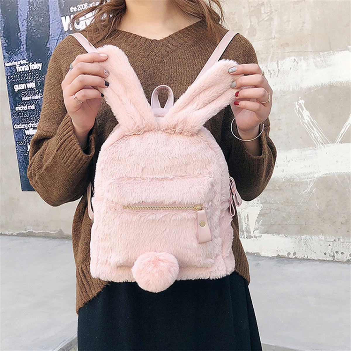 Ein rosa Kaninchen-Rucksack mit Schlappohren und einem flauschigen Schwanz. Der Rucksack ist auf einer Person.