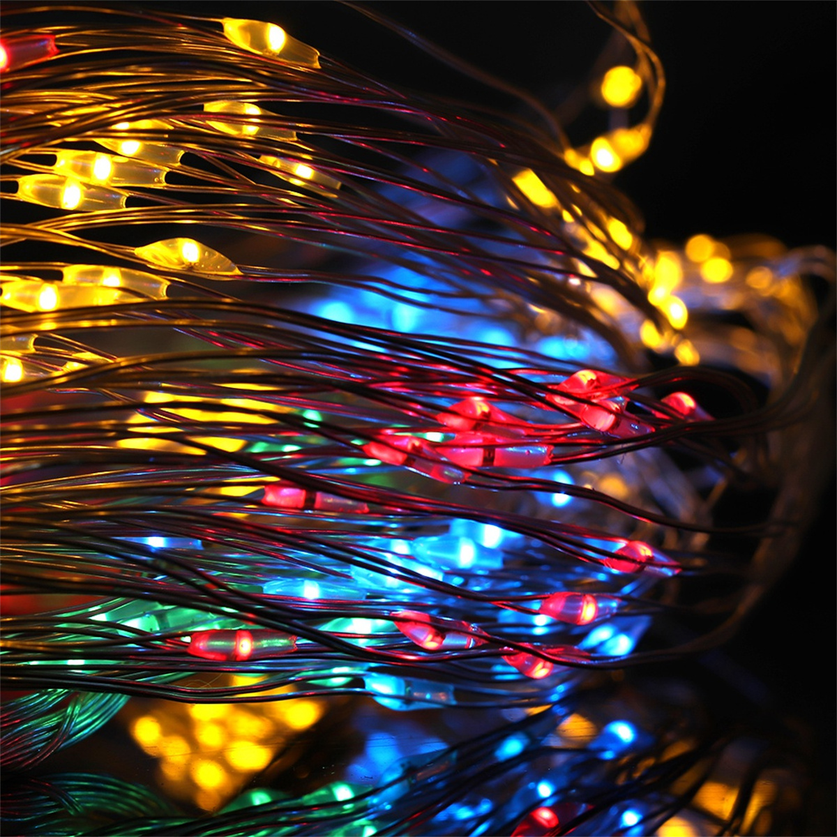 Nahaufnahme von bunten Lichterketten mit gelben, roten, blauen und grünen Lichtern auf dunklem Hintergrund.