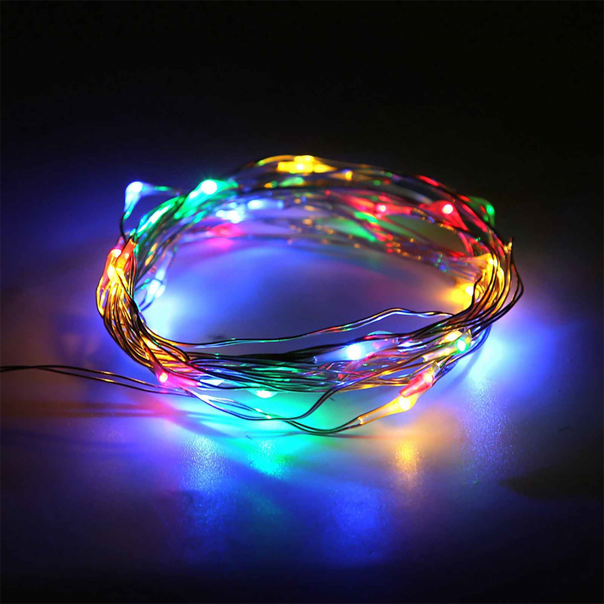 Eine Spule aus bunten LED-Lichterketten, die mit verschiedenen Farben auf dunkler Oberfläche leuchten.