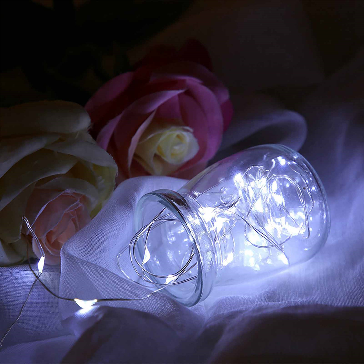 Glasbehälter mit Lichterketten und Blumen. Weichzeichner, romantische Umgebung.