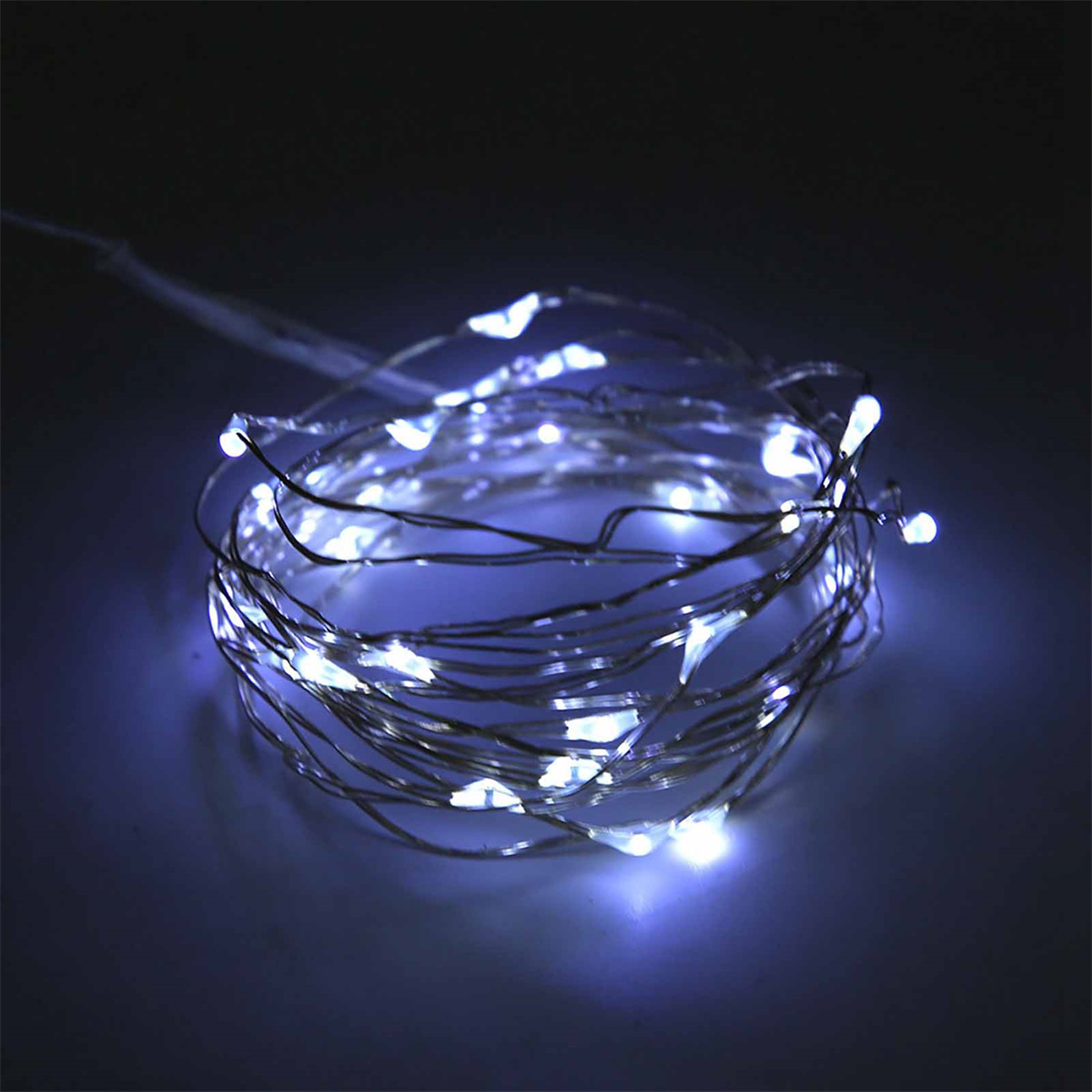 Eine aufgerollte Lichterkette mit weißen LEDs vor dunkelblauem Hintergrund.