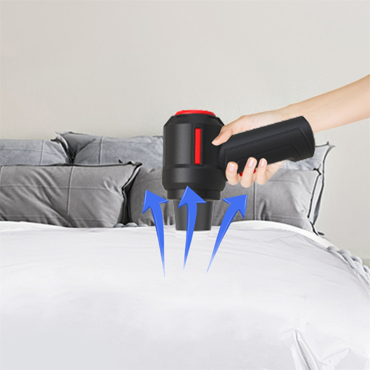 Eine Hand verwendet ein schwarzes Gerät, um ein Bett abzusaugen, blaue Pfeile zeigen die Richtung an.