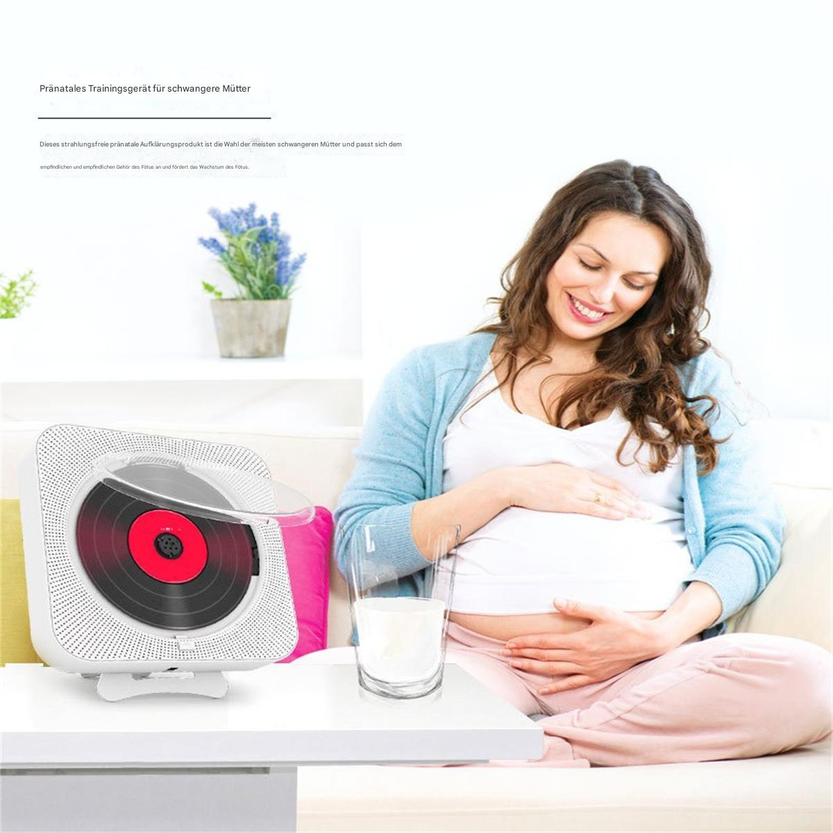 Eine schwangere Frau sitzt und hält ihren Bauch. Ein weißer Disc-Player und ein Glas Milch sind in der Nähe.