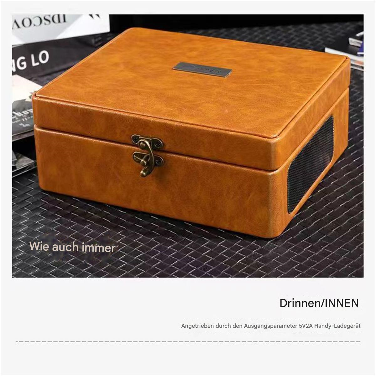 Eine braune Lederbox mit einem Riegel. Der Text unten lautet 'Drinnen/INNEN'. Der Hintergrund ist unscharf.