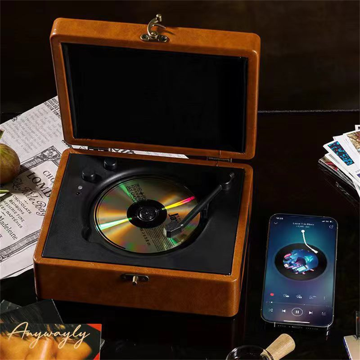 Ein Vintage-Plattenspieler mit CD. Ein Smartphone mit Musik-App liegt daneben auf einem Tisch.