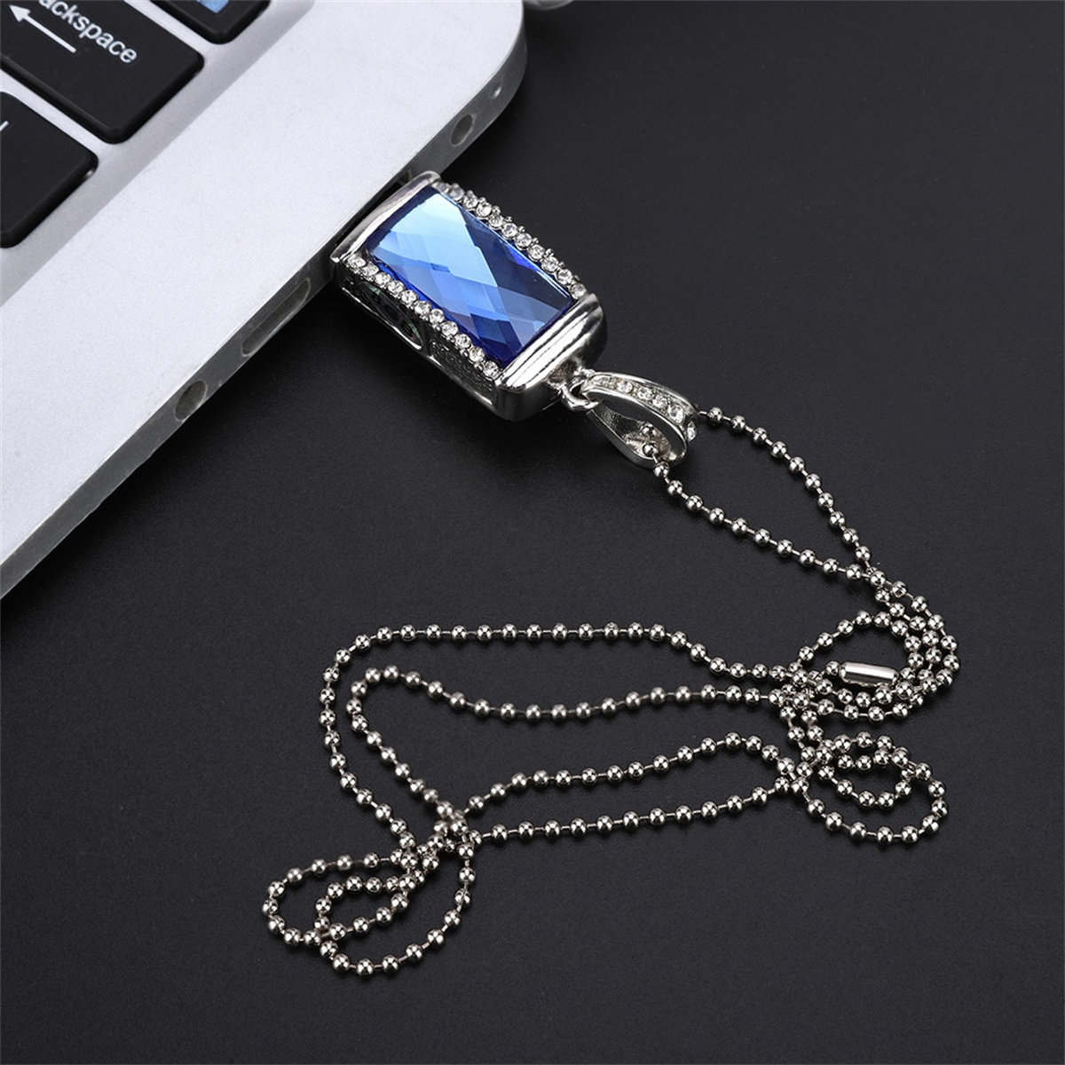Blauer Schmuck-USB-Stick an Laptop angeschlossen, mit silberner Kette.