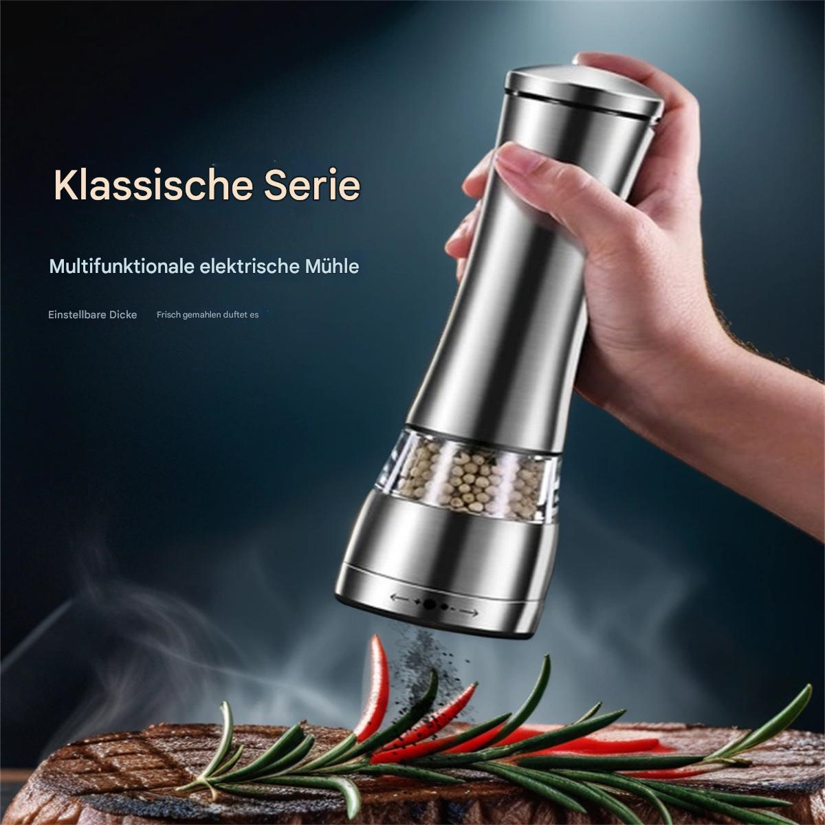 Eine Hand hält einen silbernen elektrischen Grinder über Steak, Gewürze fallen. Chili und Rosmarin schmücken die Szene.